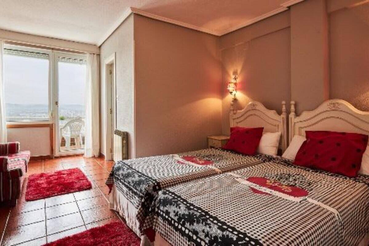 Ein Schlafzimmer mit einem großen Bett, einem Nachttisch, einem roten Teppich und einem Fenster mit Blick.