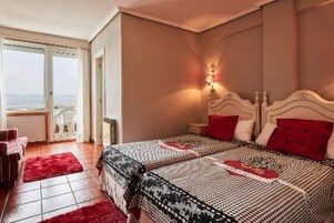 A bedroom with a large bed, a nightstand, a red rug, and a window with a view.
