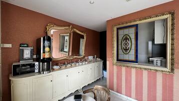 A dining area with a white cabinet, a coffee machine, and a clock displaying 17:03.