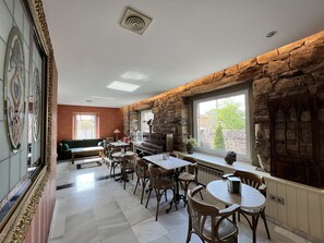 A dining area with stone walls, a piano, and a view of the outdoors. - Posada Villa Rosa (Reinosa)