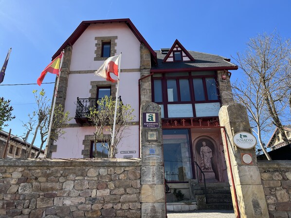 A traditional building with a stone facade, a balcony with a wrought iron railing, and a sign indicating it is a rural lodging.