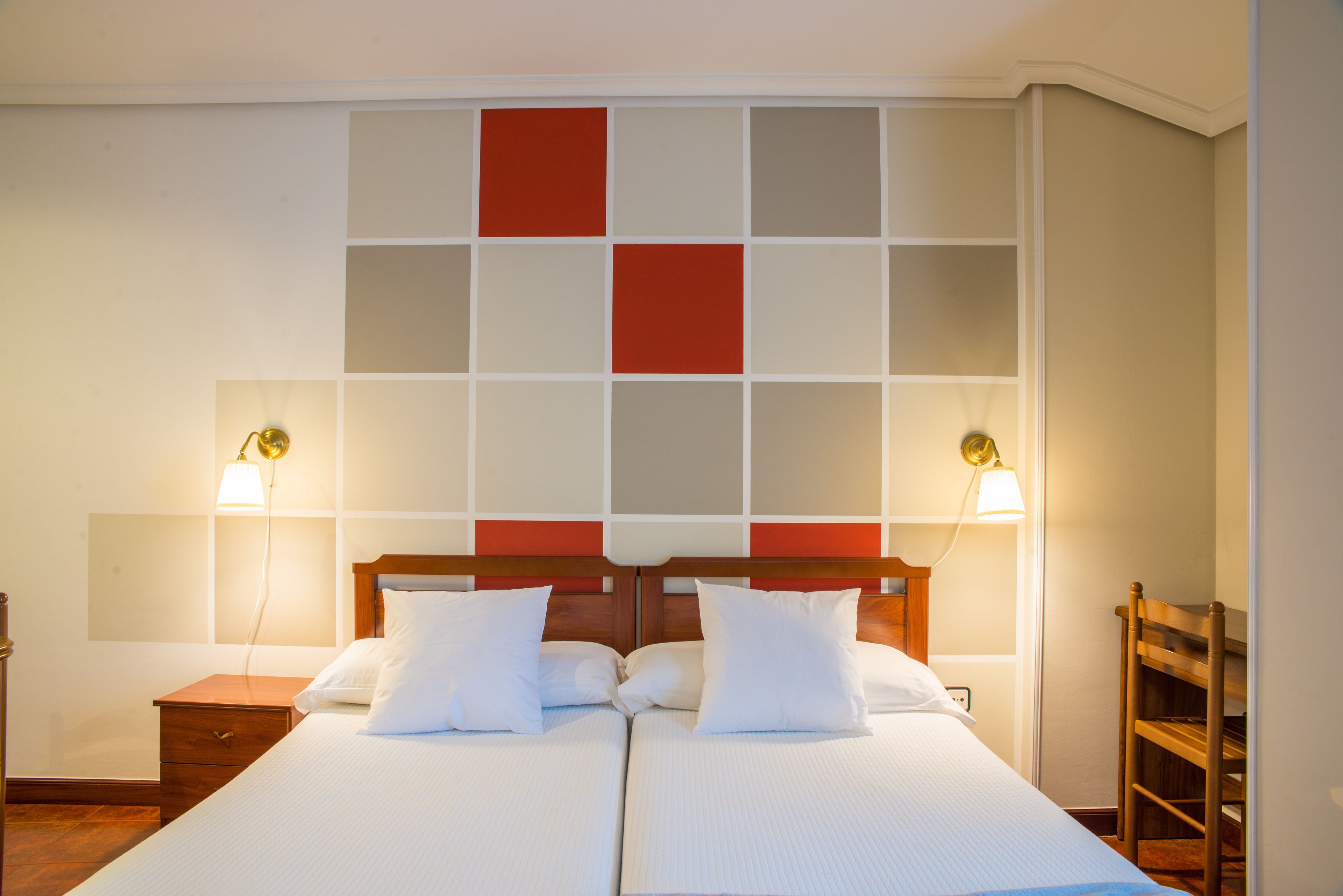 Una cama doble con ropa de cama blanca, un cabecero de madera y dos lámparas de noche.