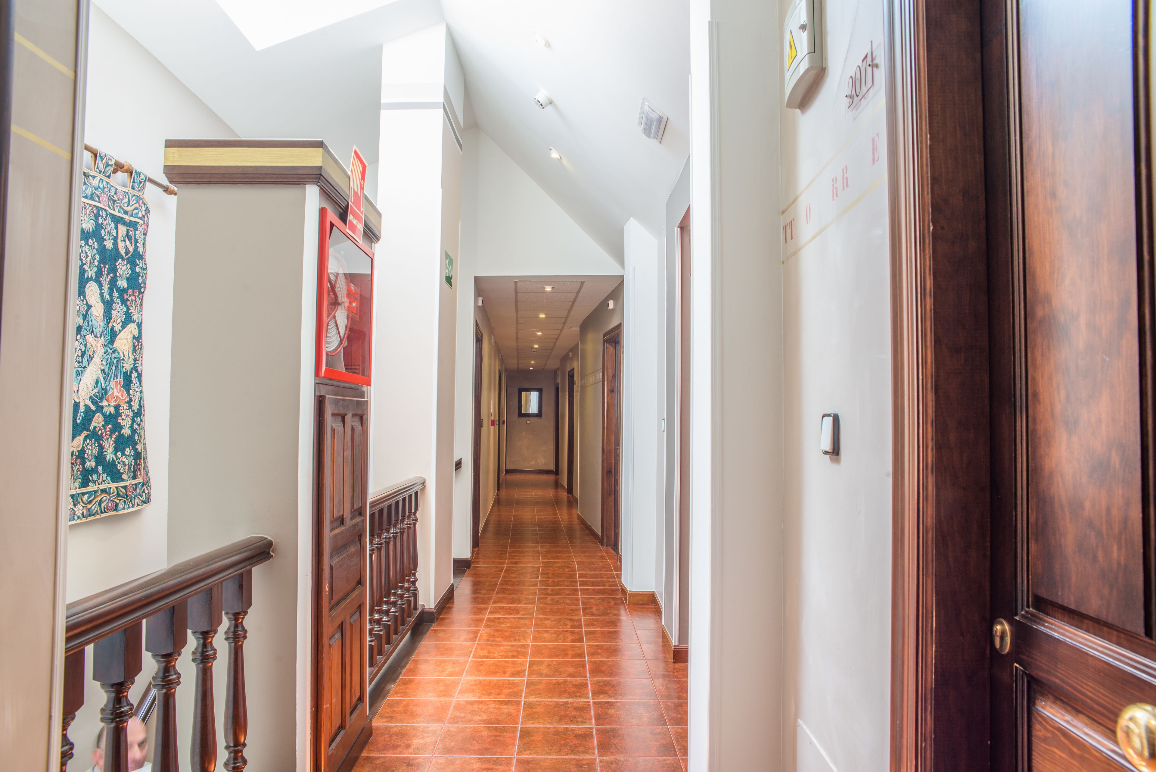 A long, narrow hallway with a wooden staircase on the left and a wooden door on the right.