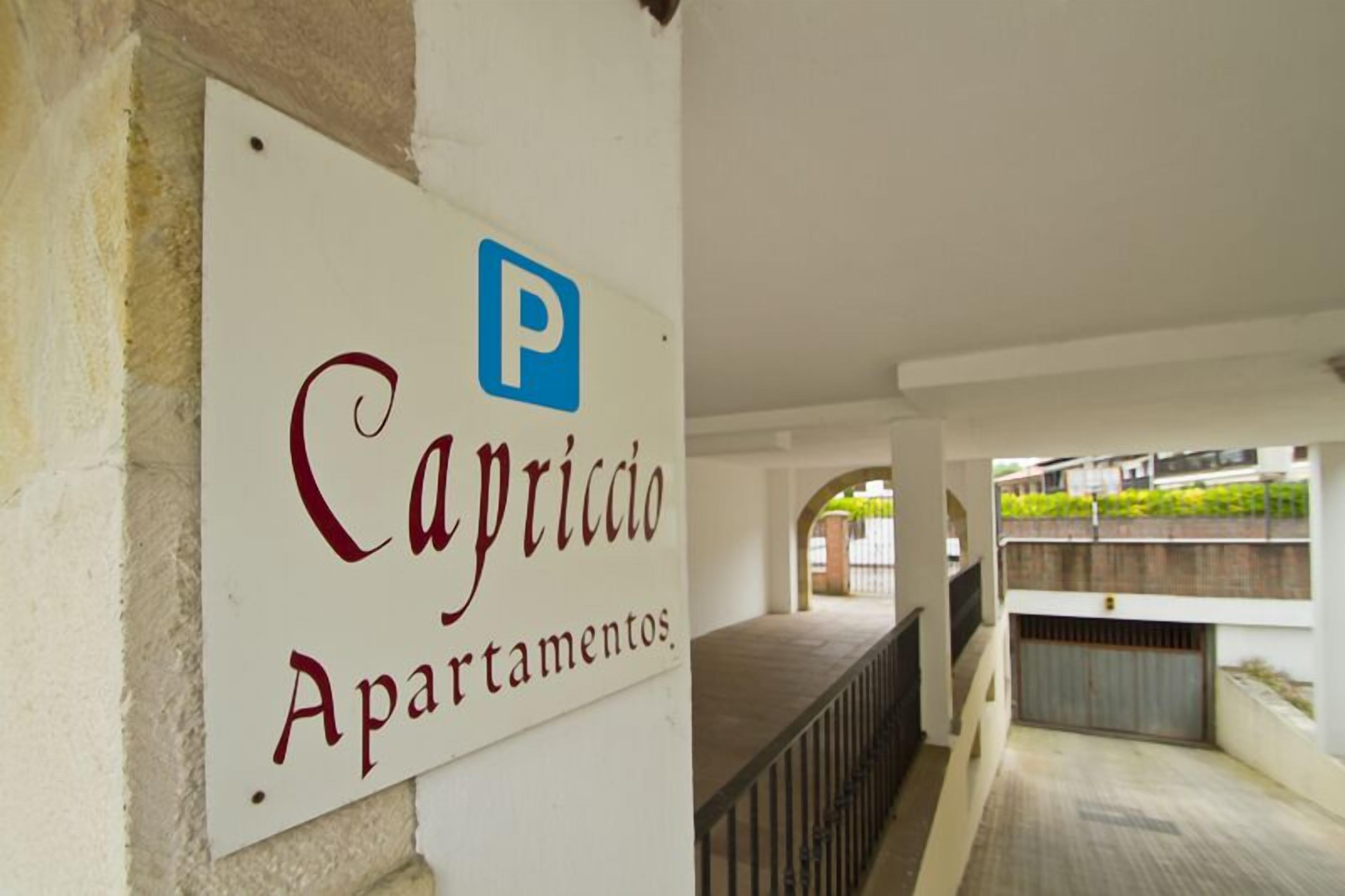 Un cartel que indica 'Capriccio Apartamentos' con un símbolo de estacionamiento.