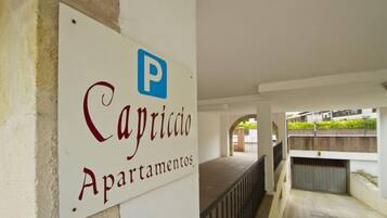 Un cartel que indica 'Capriccio Apartamentos' con un símbolo de estacionamiento.