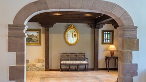 Un arco de entrada a una habitación con un banco, un espejo, una lámpara y un cuadro en la pared.
