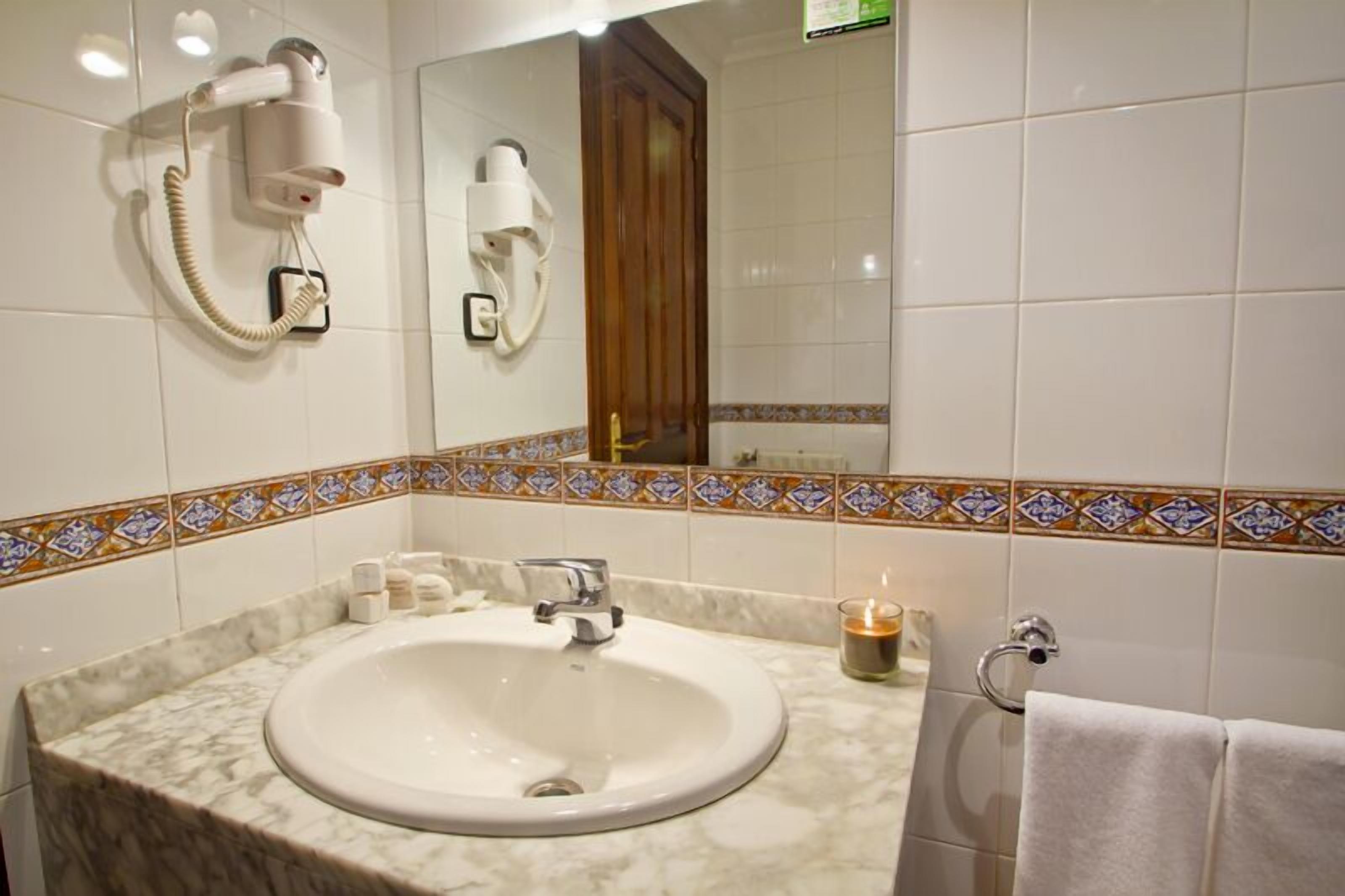 A bathroom with a marble sink, a hairdryer, a mirror, and a towel rack.