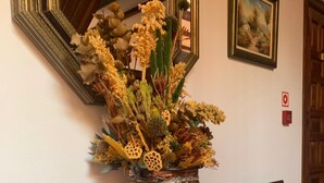 A copper vase with dried flowers on a wooden cabinet in a room with a mirror and a framed painting on the wall. - Hotel Siglo XVIII (Santillana del Mar)