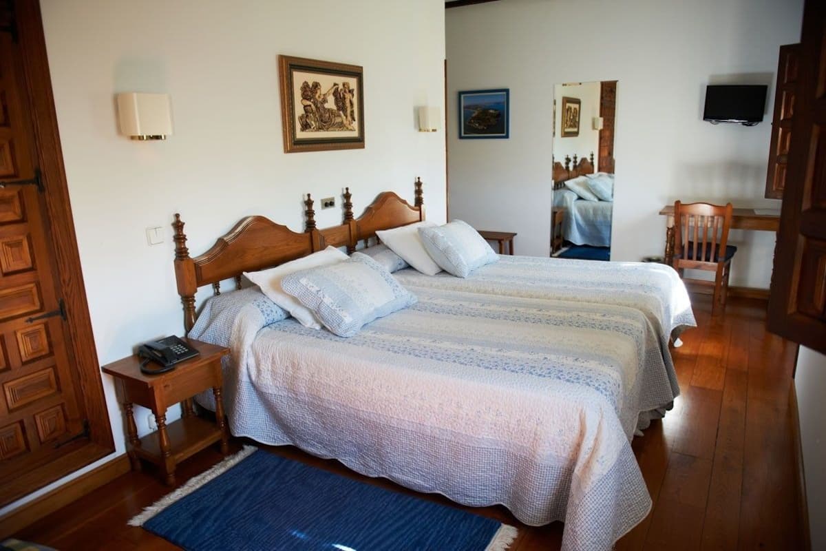 Una cama doble con cabecera de madera, una mesita de noche con un teléfono y una alfombra azul.