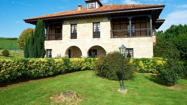 A two-story stone building with a tiled roof, multiple windows, and a balcony. - Hotel Siglo XVIII (Santillana del Mar)