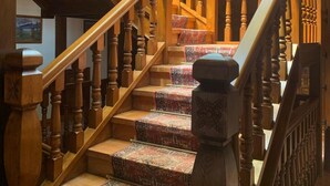A wooden staircase with ornate balusters and carpeted steps. - Hotel Siglo XVIII (Santillana del Mar)