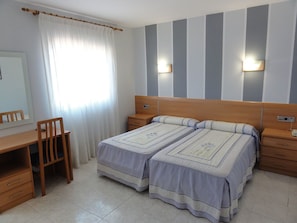 A bedroom with two beds, a desk, a chair, and a mirror. - Vivero Playa (Suances)