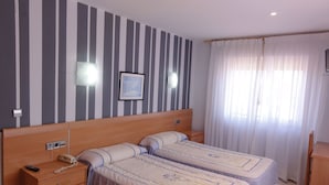 A double room with two beds, a wooden nightstand, a telephone, and a framed picture on the wall. - Vivero Playa (Suances)