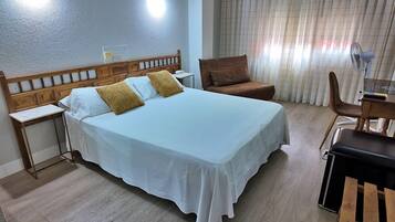 Une chambre d’hôtel avec un lit, un bureau, une chaise et une fenêtre avec des rideaux.