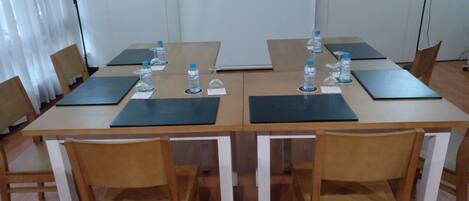 Un salón de conferencias con una mesa larga, sillas, botellas de agua y tarjetas de identificación.
