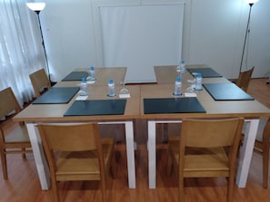 Un salón de conferencias con una mesa larga, sillas, botellas de agua y tarjetas de identificación.