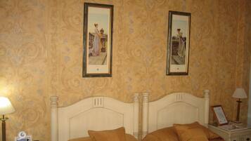 Een hotelkamer met een groot bed, twee ingelijste foto's aan de muur, een nachtkastje met een lamp, en een bijzettafeltje met een lamp.