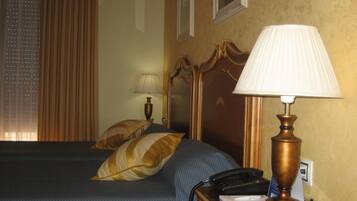 A hotel room with a bed, a nightstand with a lamp, a telephone, and a wall-mounted picture.