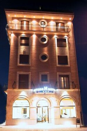 A multi-story hotel with a brick facade, illuminated windows, and a sign indicating it is a hotel. - Hotel Santiago (Benavente)
