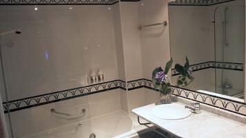 Un baño con ducha de vidrio, bañera y lavamanos con espejo.
