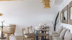 A modern interior with exposed wooden beams, a round dining table with chairs, a sofa with cushions, and a hanging light fixture. - Hotel La Torreta (Altafulla)
