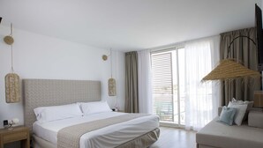 A modern bedroom with a large bed, a sofa, a hanging light, and a window with curtains. - Hotel La Torreta (Altafulla)