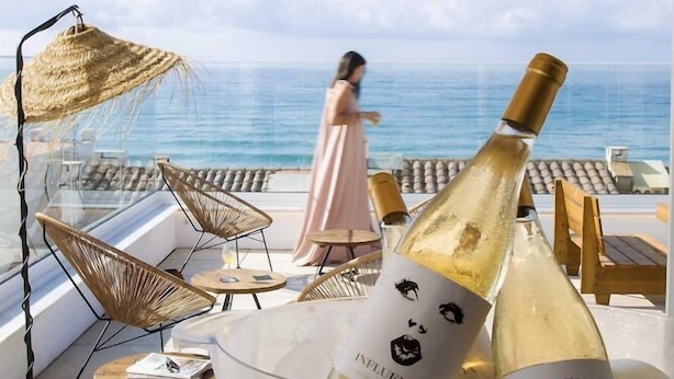 A balcony with a view of the sea, a bottle of champagne, and a person in a pink dress. - Hotel La Torreta (Altafulla)