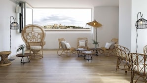 A spacious living room with wicker furniture, a large window with a view, and a ceiling light fixture. - Hotel La Torreta (Altafulla)