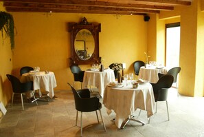A dining area with round tables, black chairs, and a mirror on the wall. - Font Del Genil (Arseguel)