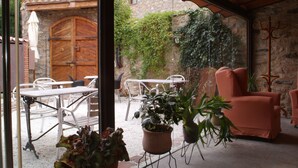 An interior space with a stone wall, a wooden door, and a view of a mountainous landscape. - Font Del Genil (Arseguel)