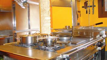 Une cuisine professionnelle équipée d’appareils en acier inoxydable, avec des casseroles sur la cuisinière et divers ustensiles de cuisine.