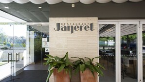L’entrée d’un restaurant, avec une enseigne indiquant « Restaurant Janeret » et des plantes en pot devant.