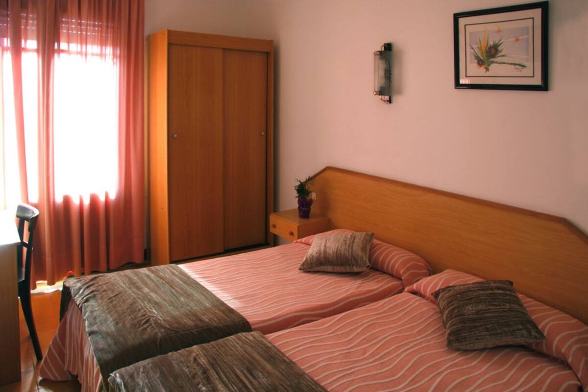 A bedroom with a bed, a nightstand, a wardrobe, and a framed picture on the wall.