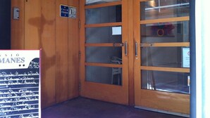 Una puerta de madera con paneles de vidrio, un letrero que indica un restaurante y una pizarra con el menú.