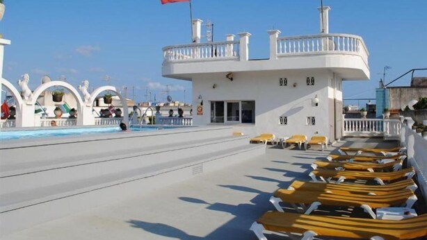 A poolside area with lounge chairs and a building with balconies. - Las Americas (Blanes)