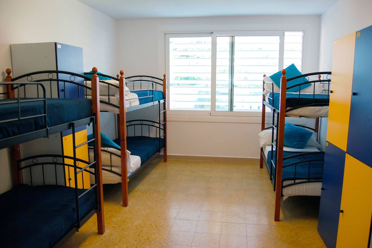 Een studentenkamer met stapelbedden, een raam en een kledingkast.