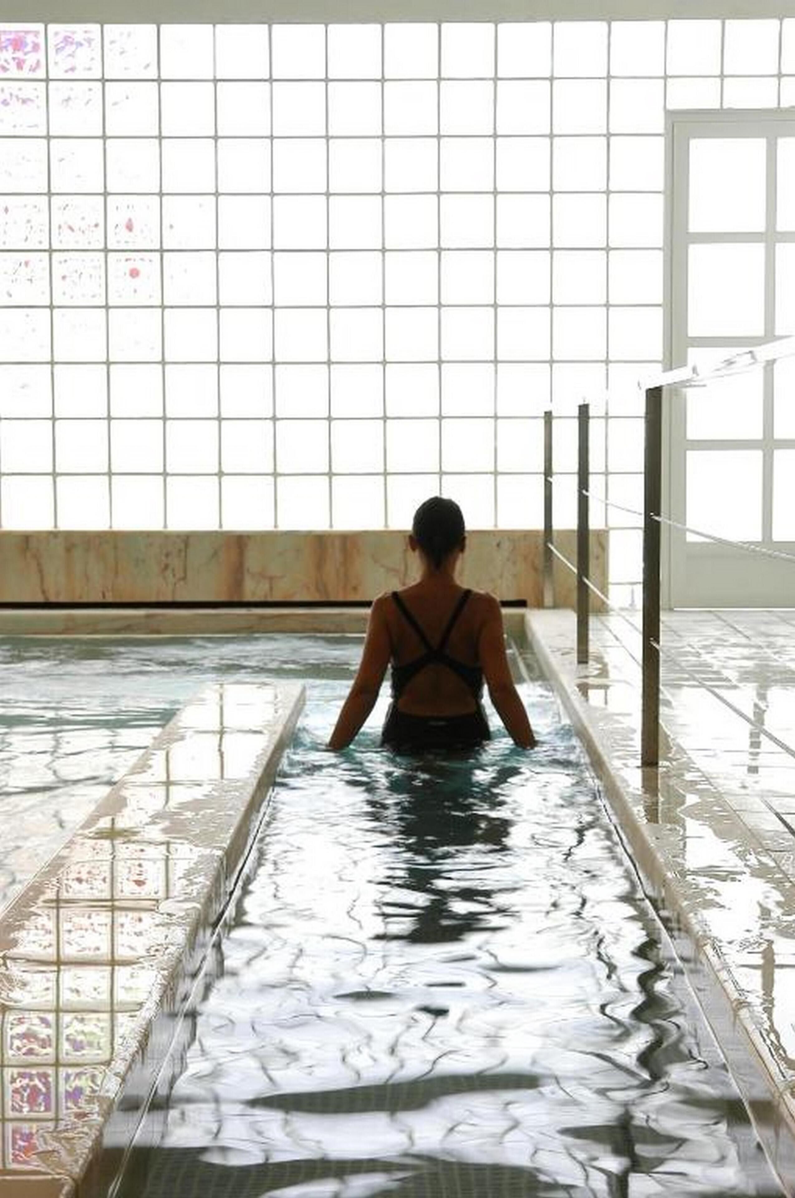 Una persona en una piscina con una pared de azulejos y una ventana al fondo.