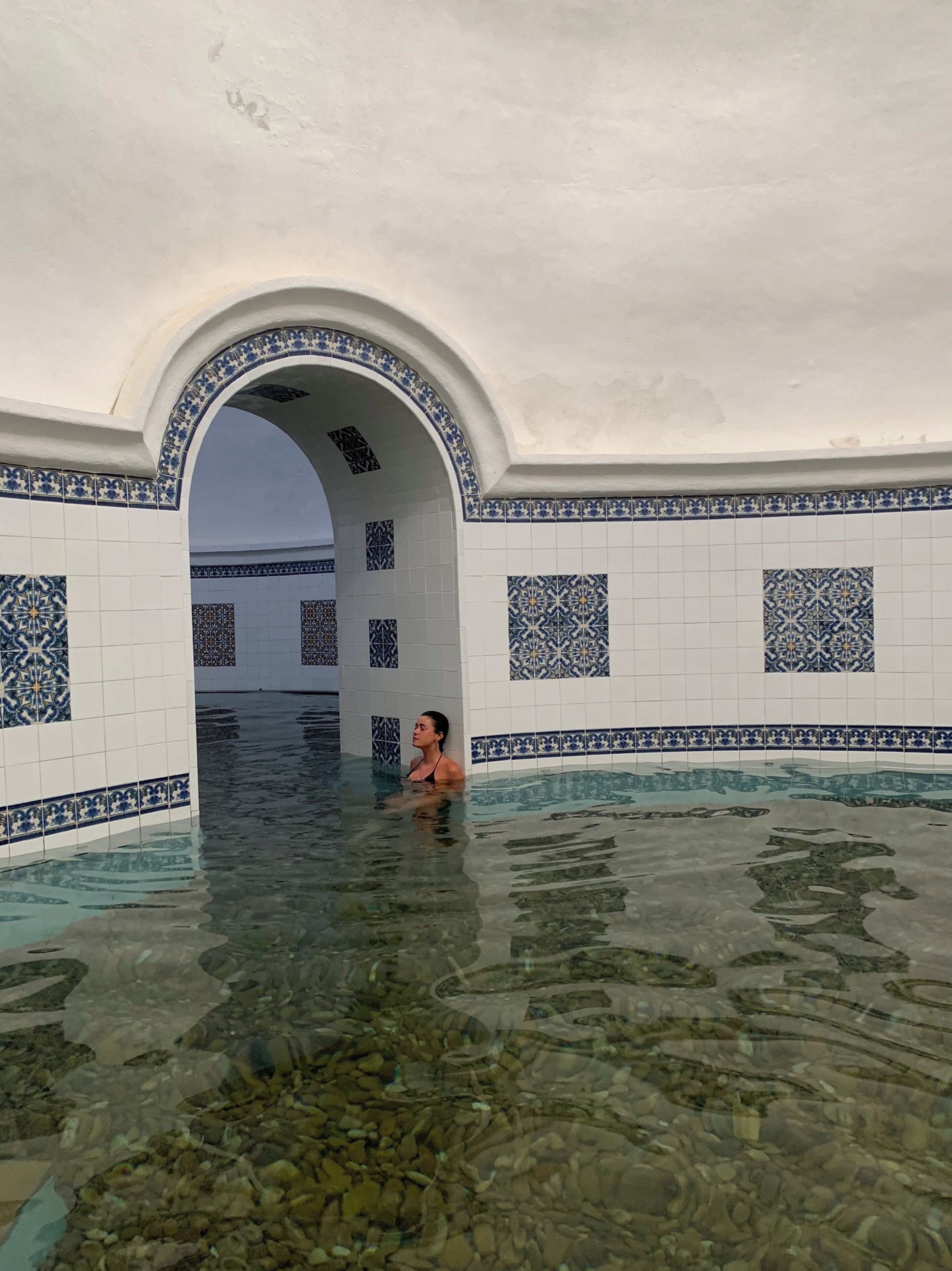 A pool area with tiled walls and an arched entrance.
