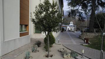 Un jardín ajardinado con un sendero que lleva a un edificio de fachada blanca y paneles de madera.