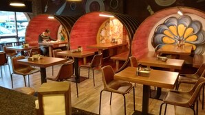 Interior de restaurante con cabinas y mesas, suelo de madera y un mural en la pared.