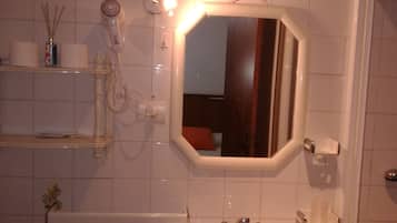 A bathroom with a white sink, a mirror, and a hairdryer on a shelf.