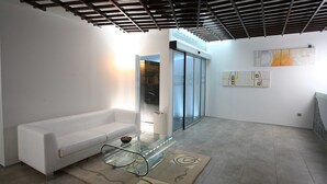 Un moderno salón con un sofá blanco, una mesa de centro de vidrio y una alfombra estampada.