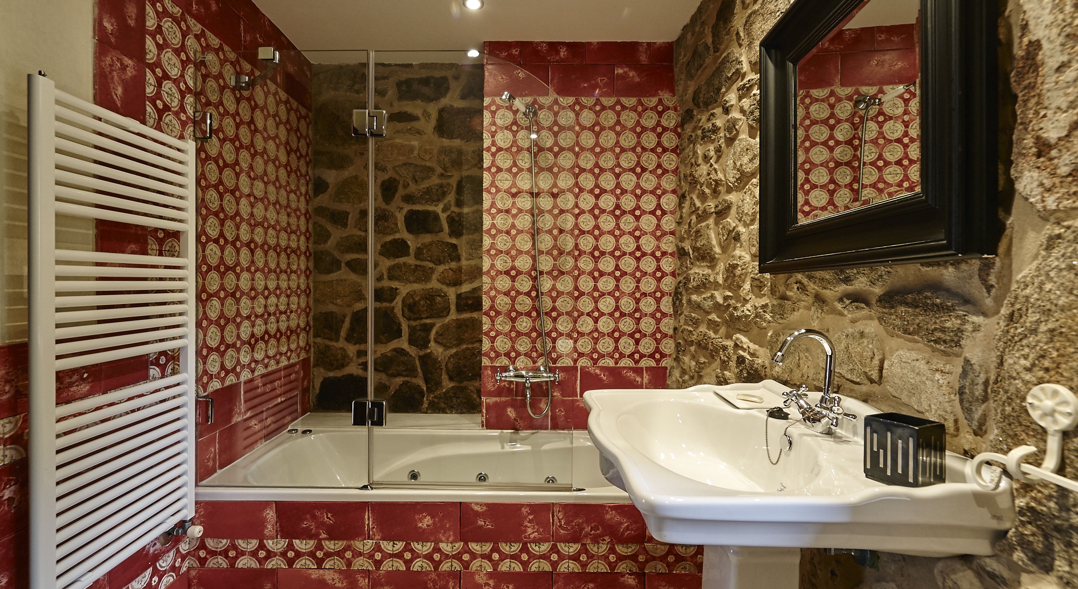 Ein Badezimmer mit Steinwand, Badewanne, Dusche und Waschbecken.