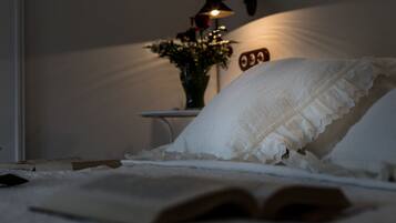 A bedroom with a bed, an open book, a bedside lamp, and a wall clock.