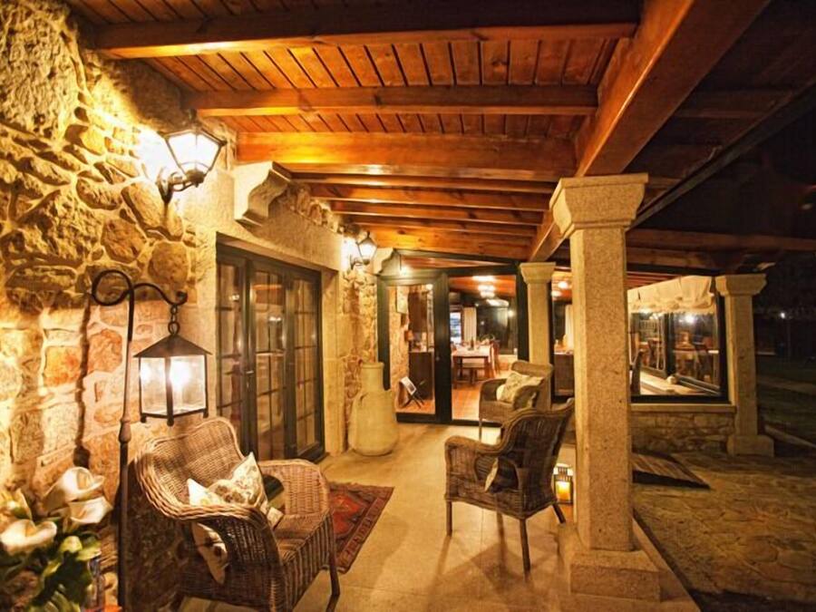 Un área de patio techada al aire libre con paredes de piedra, mobiliario de mimbre y techo de madera.