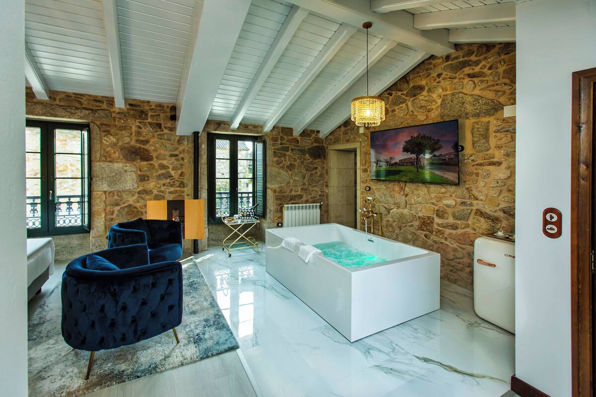 Un baño espacioso con una bañera grande, paredes de piedra y un diseño moderno.