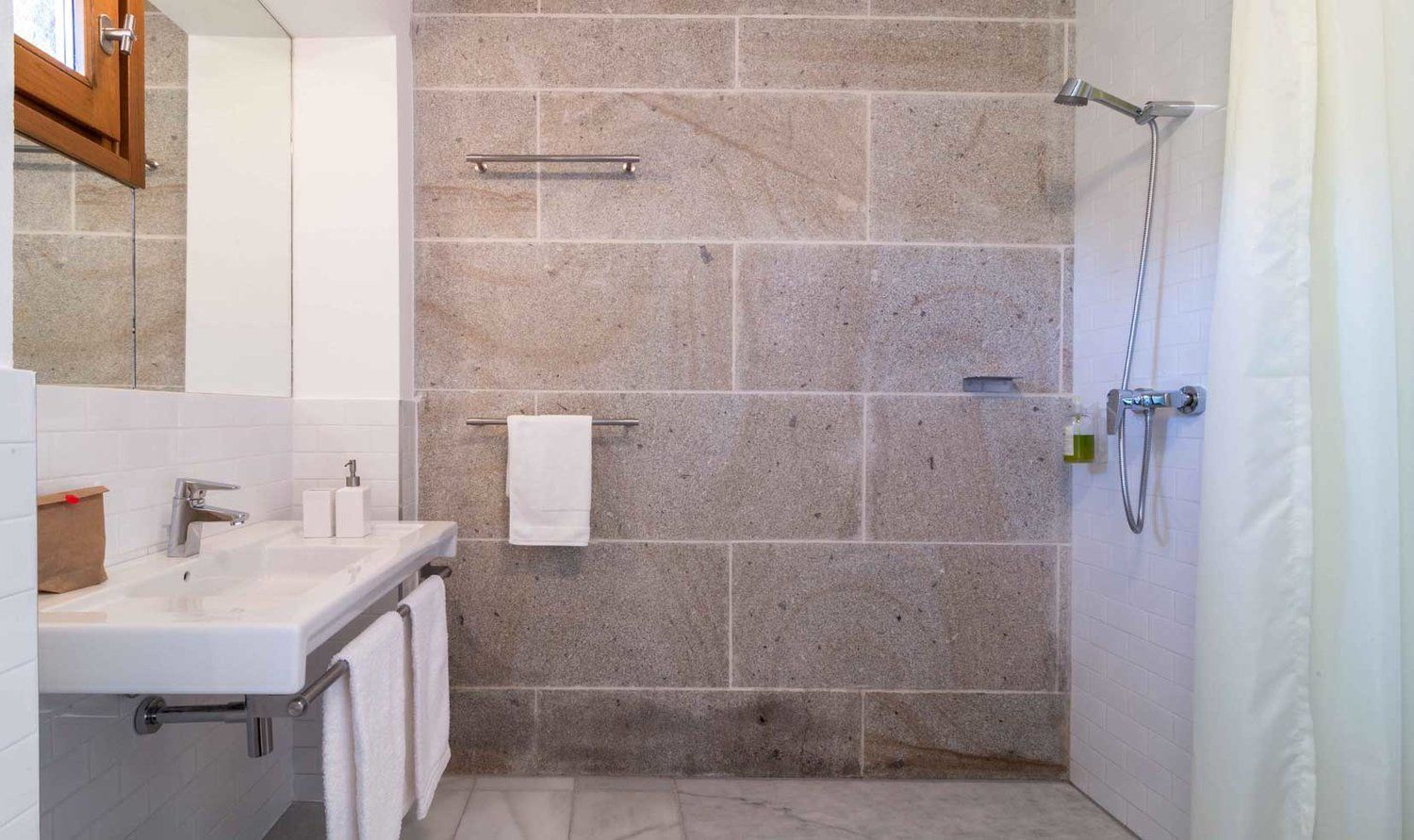 Ein Badezimmer mit Waschbecken, Spiegel, Handtuchhalter und Dusche.