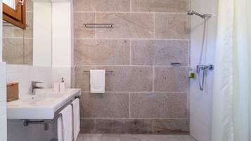 Ein Badezimmer mit Waschbecken, Spiegel, Handtuchhalter und Dusche.