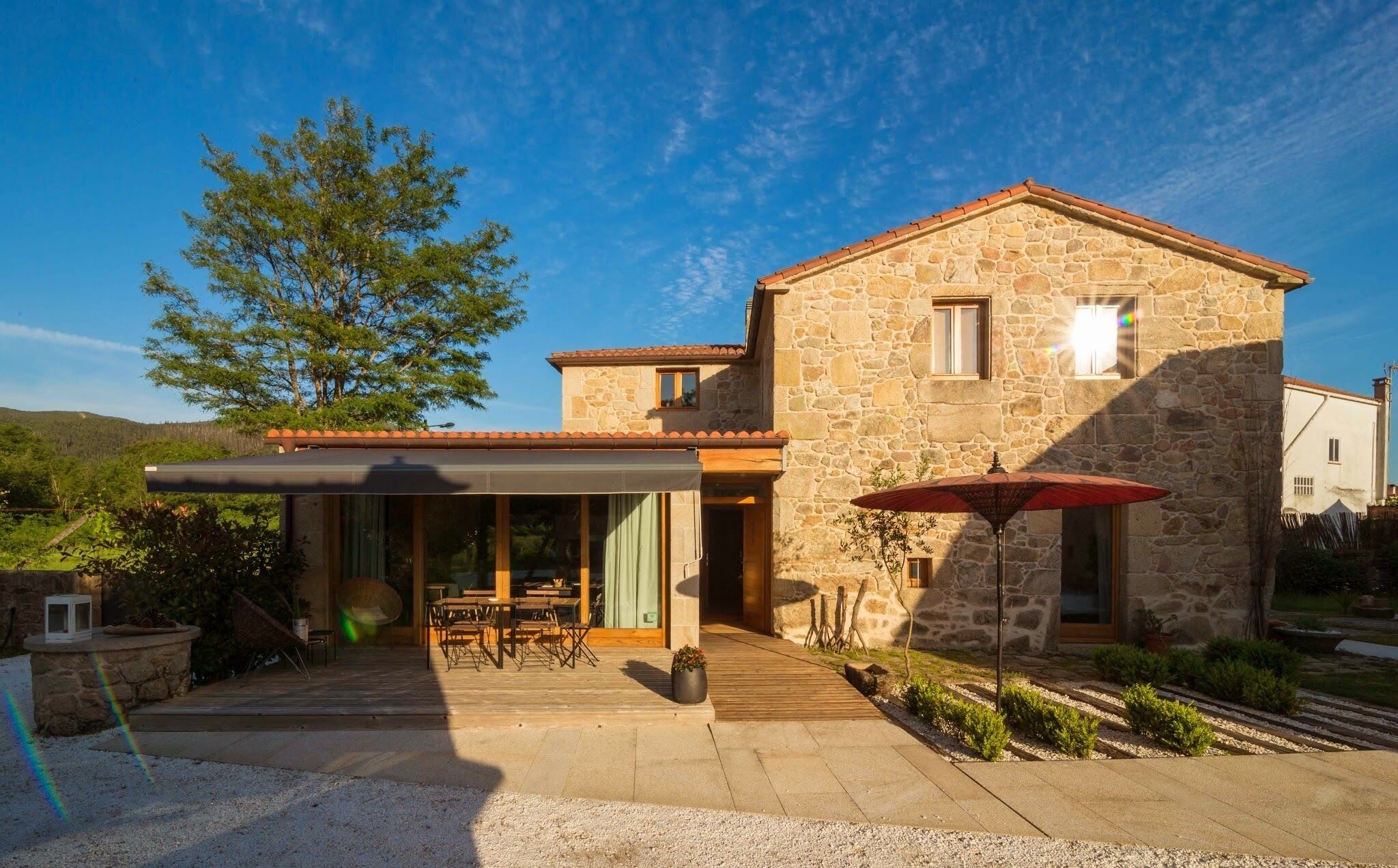 A stone building with a covered patio, outdoor seating, and a view of the surrounding landscape.