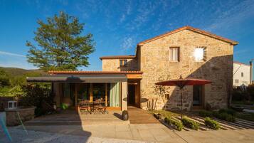 A stone building with a covered patio, outdoor seating, and a view of the surrounding landscape.